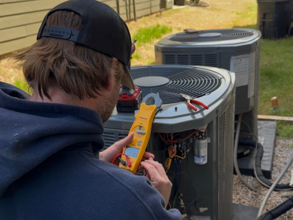 Tech servicing outdoor unit, checking for proper fuction.