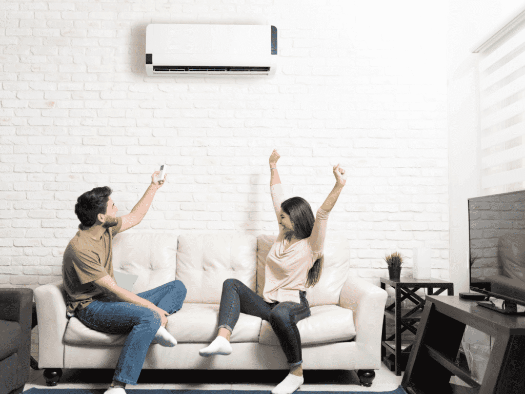 mini split on wall with couple on couch below expressing happiness