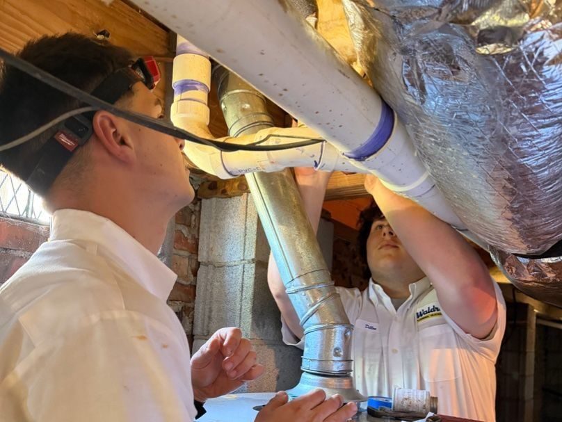 Two Waldrop plumbers inspecting duct leak.